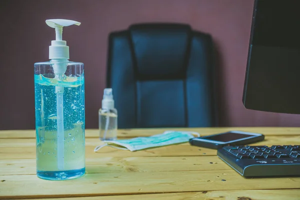 idea of working at home between quarantine, sanitizer hand gel placed on a wooden desk, with a smartphone computer keyboard, medical mask and alcohol spray, preventing the spread of Coronavirus.