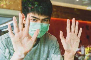 Taze kahve dükkanında dikilen genç bir adamın resmi. Cavid-19 salgını sırasında dükkanda tıbbi maske takıyor, koroner hastalığı sırasında insanların normal hayatı (Covid-19).