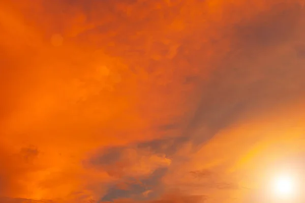 The sun shines against orange clouds is a dazzling natural phenomenon in the colorful combination of colors and shades of clouds. the beauty of the sun with the softness of the swaying orange clouds.