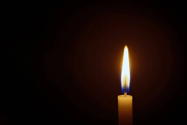 Beyaz mum alevi siyah bir zemin üzerine kapanır, mum karanlıkta yanar, yanan mum alevi ışık arka planında Hıristiyan inancının bir sembolüdür..