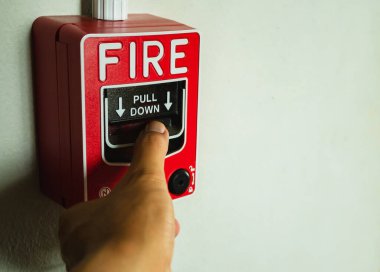 Binalarda ve ofislerde alarm düğmeleri var. Elin yangın alarmına basıyor. Acil bir durumda alarm düğmesine basıldığında.