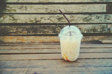 Ahşap bir masada buzlu kahve, bulanık ahşap bir masada buzlu kahve, arka planda ahşap duvar.                               