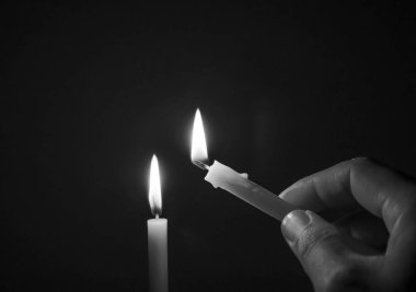 Siyah ve beyaz görüntü konsepti, karanlık bir odada mum ışığı, geceleri bir mum alevi.