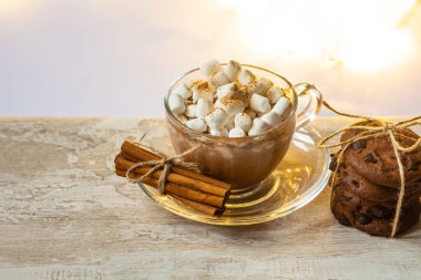 Bir fincan sıcak çikolata, marşmelov, tarçın ve ahşap arka planda anason..