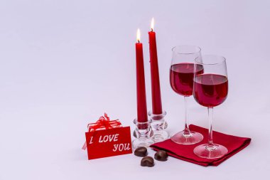 Kırmızı şarap, çikolata ve beyaz arka planda mumlar..