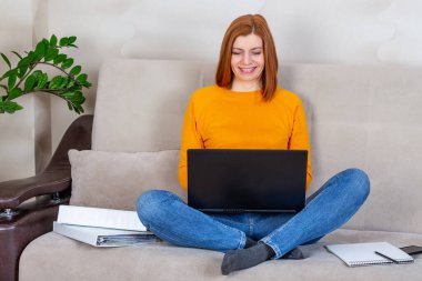 Çekici kadın kanepede oturuyor ve dizüstü bilgisayarla çalışıyor.