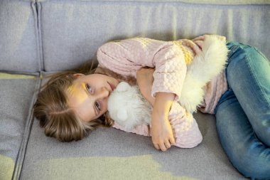 Yorgun küçük kız evdeki kanepede yatıyor.