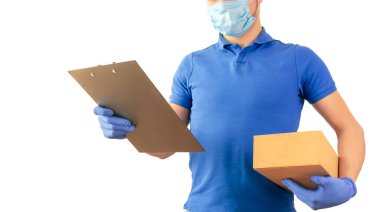 Mavi tişörtlü teslimatçı üniformalı steril yüz maskesi eldivenli, elinde karton kutular ve beyaz arka planda izole tablet olan. Kurye servisinde çalışan adam karantina pandemik koronavirüs virüsü konsepti