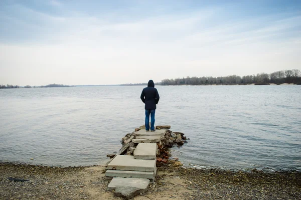 A  man standing alone by the water — Stock Photo, Image