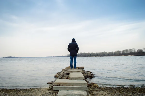 A  man standing alone by the water — Stock Photo, Image