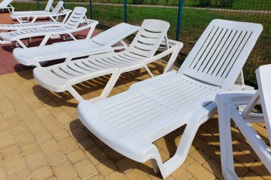 Havuzun önünde beyaz plastik güneşlikler. Kimse yok, önden bak.