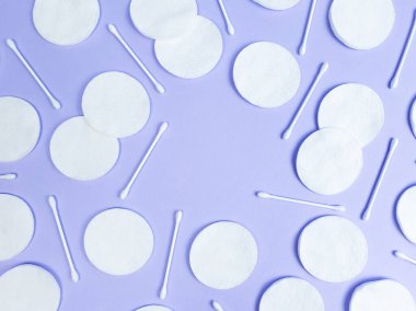 Açık mor arka planda pamuk pedler ve çubuklar. Üst görünüm, ürün veya metin için boş yer. Düzleştirme biçimi, desen