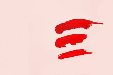 Pembe arka planda üç kat mat kırmızı ruj, kozmetik konsepti. Üst görünüm, yaşam tarzı.