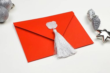 Beyaz balmumu damgalı kırmızı zarf ve hediye çeki ya da davetiye için ipek püskül ve gümüş Noel oyuncakları.