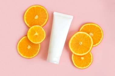 Açık pembe arka planda krema ve portakal dilimleri için kaplama. Vücut losyonu ve tuvalet malzemeleri için konteynır. Profesyonel bakım ürünleri için tüp. Cilt bakımı ve reklam konsepti. Model biçimi, şablon