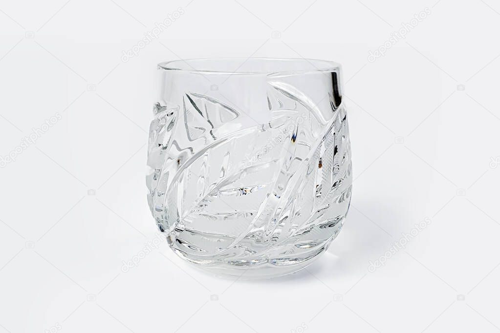Crystal glass with leaf pattern isolated on white background. Front view of whiskey glass.
