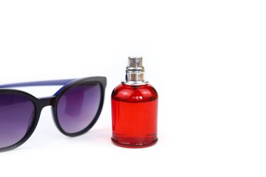 Markasız parfüm spreyi kırmızı şişe ve mor güneş gözlüğü beyaz arka planda izole edilmiş ve fotokopi alanı var. Eau de Tuvalet, ön manzara, model.