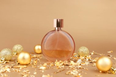 Damgasız yuvarlak parfüm şişesi, altın noel topları ve altın arka planda kağıt çatapat parçaları. Damgalamak ve etiketlemek için saydam cam parfüm şişesi. Eau de Tuvalet. Model