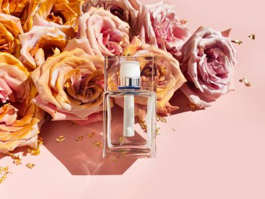 Damgasız parfüm şeffaf beyaz şişe, moda gölgesi, pembe altın güller ve açık pembe arka planda altın kağıt parçaları. Üst görünüm, Lüks düz görünüm, kopyala boşluk.