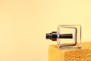 Altın kaplama kürsüde yan yatmış, markasız, siyah bir parfüm şişesi. Ön görünüm, model, şablon