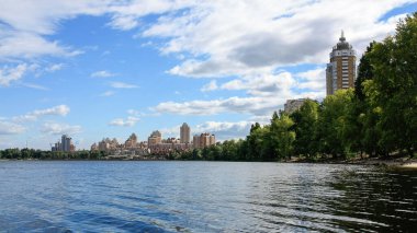 sakin nehir manzarası ve bulutlu gökyüzü arka planındaki ağaçların arkasındaki binalar, doğa kavramı, Kyiv, Ukrayna
