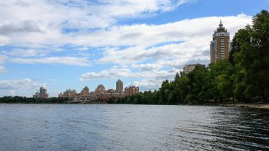 sakin nehir manzarası ve bulutlu gökyüzü arka planındaki ağaçların arkasındaki binalar, doğa kavramı, Kyiv, Ukrayna