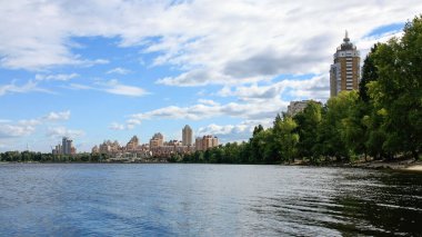 sakin nehir manzarası ve bulutlu gökyüzü arka planındaki ağaçların arkasındaki binalar, doğa kavramı, Kyiv, Ukrayna