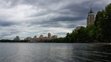 sakin nehir manzarası ve bulutlu gökyüzü arka planındaki ağaçların arkasındaki binalar, doğa kavramı, Kyiv, Ukrayna
