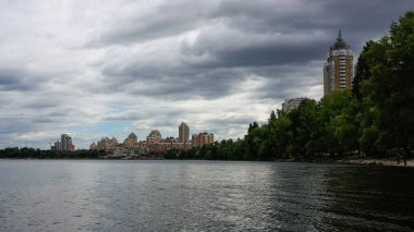 sakin nehir manzarası ve bulutlu gökyüzü arka planındaki ağaçların arkasındaki binalar, doğa kavramı, Kyiv, Ukrayna