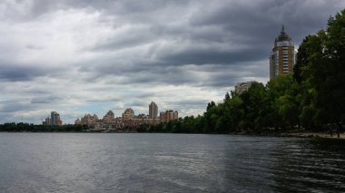 sakin nehir manzarası ve bulutlu gökyüzü arka planındaki ağaçların arkasındaki binalar, doğa kavramı, Kyiv, Ukrayna