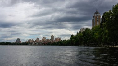 sakin nehir manzarası ve bulutlu gökyüzü arka planındaki ağaçların arkasındaki binalar, doğa kavramı, Kyiv, Ukrayna