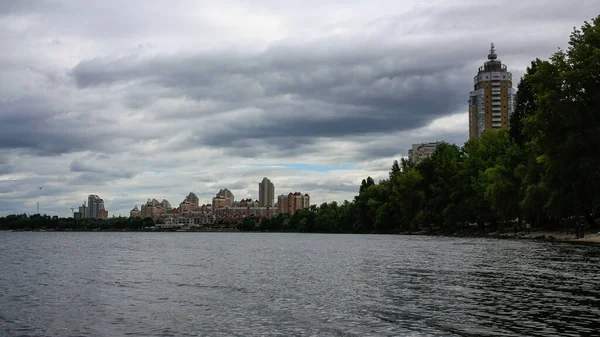 sakin nehir manzarası ve bulutlu gökyüzü arka planındaki ağaçların arkasındaki binalar, doğa kavramı, Kyiv, Ukrayna