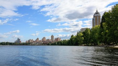 sakin nehir manzarası ve bulutlu gökyüzü arka planındaki ağaçların arkasındaki binalar, doğa kavramı, Kyiv, Ukrayna