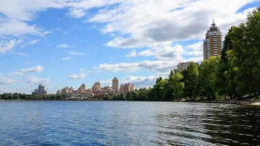 sakin nehir manzarası ve bulutlu gökyüzü arka planındaki ağaçların arkasındaki binalar, doğa kavramı, Kyiv, Ukrayna