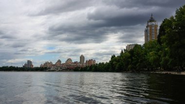 sakin nehir manzarası ve bulutlu gökyüzü arka planındaki ağaçların arkasındaki binalar, doğa kavramı, Kyiv, Ukrayna