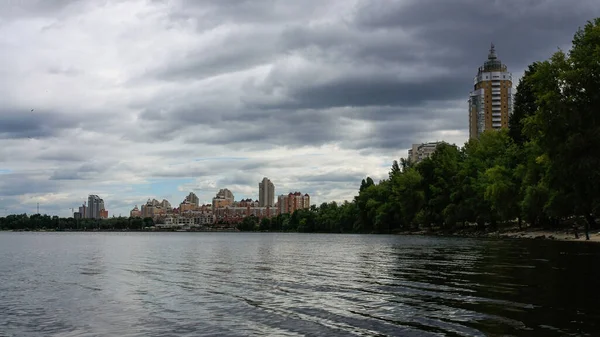 sakin nehir manzarası ve bulutlu gökyüzü arka planındaki ağaçların arkasındaki binalar, doğa kavramı, Kyiv, Ukrayna