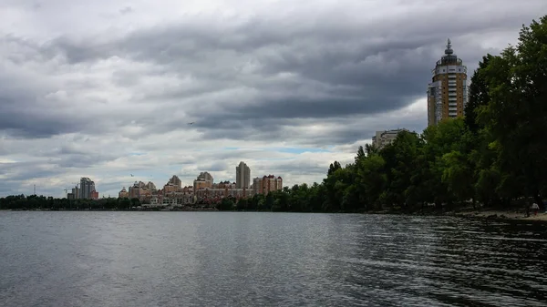sakin nehir manzarası ve bulutlu gökyüzü arka planındaki ağaçların arkasındaki binalar, doğa kavramı, Kyiv, Ukrayna