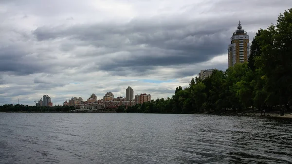 sakin nehir manzarası ve bulutlu gökyüzü arka planındaki ağaçların arkasındaki binalar, doğa kavramı, Kyiv, Ukrayna