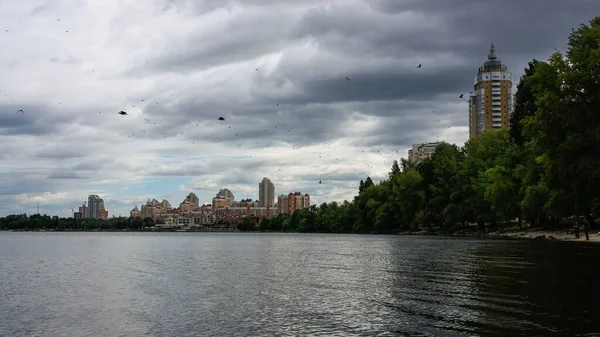 sakin nehir manzarası ve bulutlu gökyüzü arka planındaki ağaçların arkasındaki binalar, doğa kavramı, Kyiv, Ukrayna