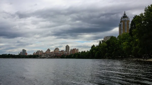 sakin nehir manzarası ve bulutlu gökyüzü arka planındaki ağaçların arkasındaki binalar, doğa kavramı, Kyiv, Ukrayna