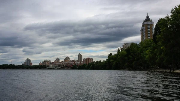 sakin nehir manzarası ve bulutlu gökyüzü arka planındaki ağaçların arkasındaki binalar, doğa kavramı, Kyiv, Ukrayna