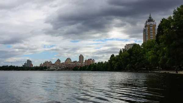 sakin nehir manzarası ve bulutlu gökyüzü arka planındaki ağaçların arkasındaki binalar, doğa kavramı, Kyiv, Ukrayna