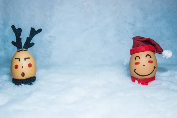 Noel / tatil konsepti tasarımı, açık mavi sahte kürk kumaşının üzerine yerleştirilmiş iki yumurtaya şirin yüzler çizerek. Arkadaşlık kavramı. Noel Baba ve geyik. Çocuk aktivitesi.