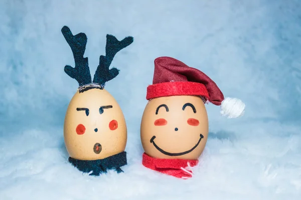 Noel / tatil konsepti tasarımı, açık mavi sahte kürk kumaşının üzerine yerleştirilmiş iki yumurtaya şirin yüzler çizerek. Arkadaşlık kavramı. Noel Baba ve geyik. Çocuk aktivitesi.
