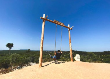 man swinging on a mountain with a view of the nature hills