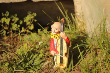 Porcelanowa figürlü pajacyka ustawiona w trawie w ogrodzie