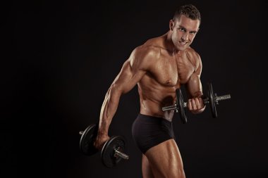 vücut geliştirmeci biri dumbbells ile yapıyor