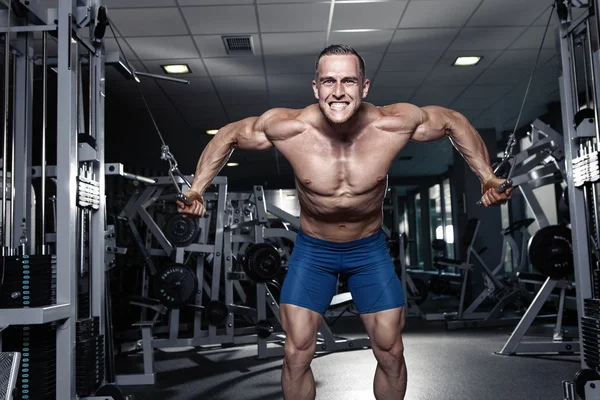 Muscular culturista chico haciendo ejercicios de entrenamiento en el gimnasio Fotos de stock libres de derechos