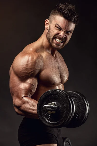 Muscular fisiculturista cara fazendo exercícios com grandes halteres — Fotografia de Stock