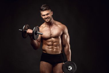 kaslı vücut geliştirmeci biri dumbbells ile yapıyor
